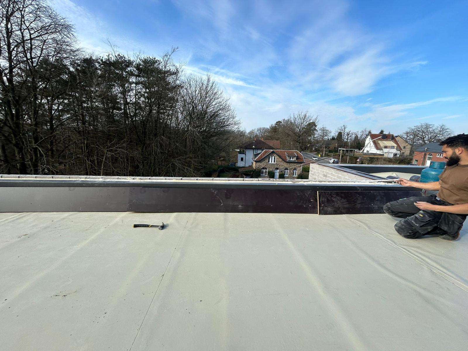 Toit plat en membrane PVC, un ouvrier termine la rive