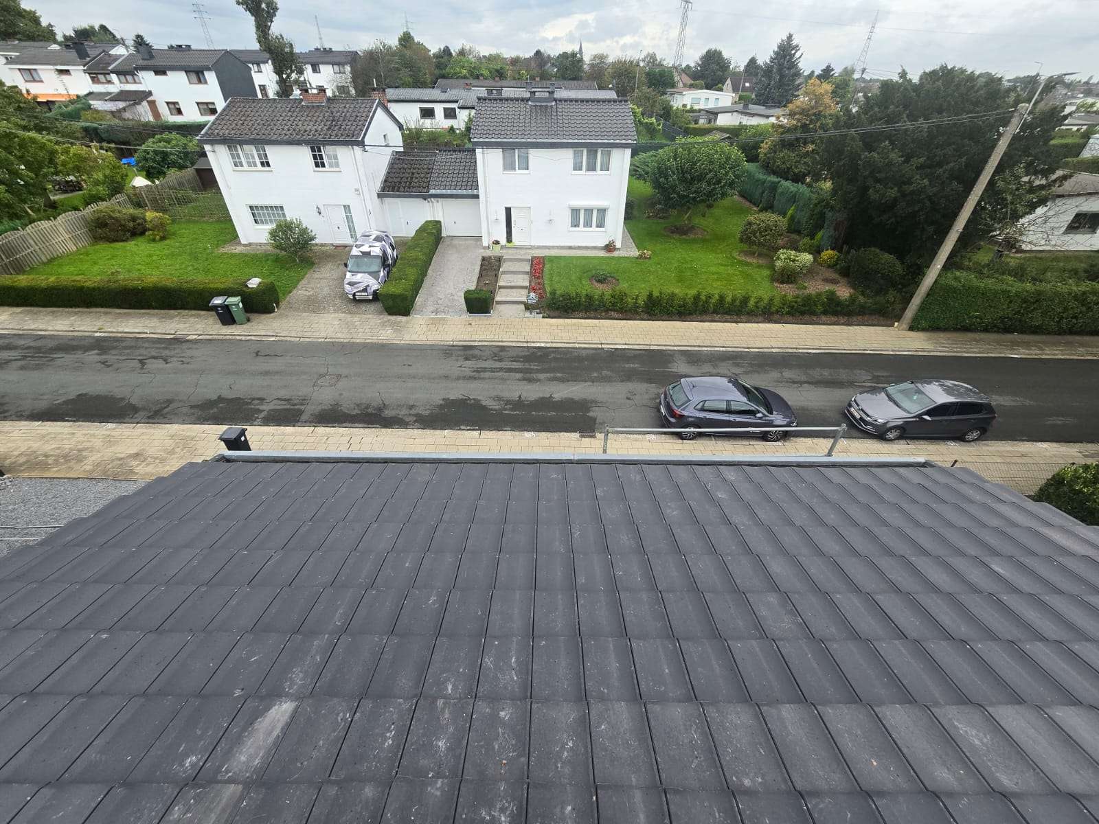 Après : toit en tuiles béton neuf avec cheminée, rue et maisons en face